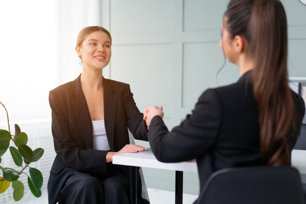 Recruiter and candidate shaking hands after an interview, representing finding the right employee through a trusted hiring process.