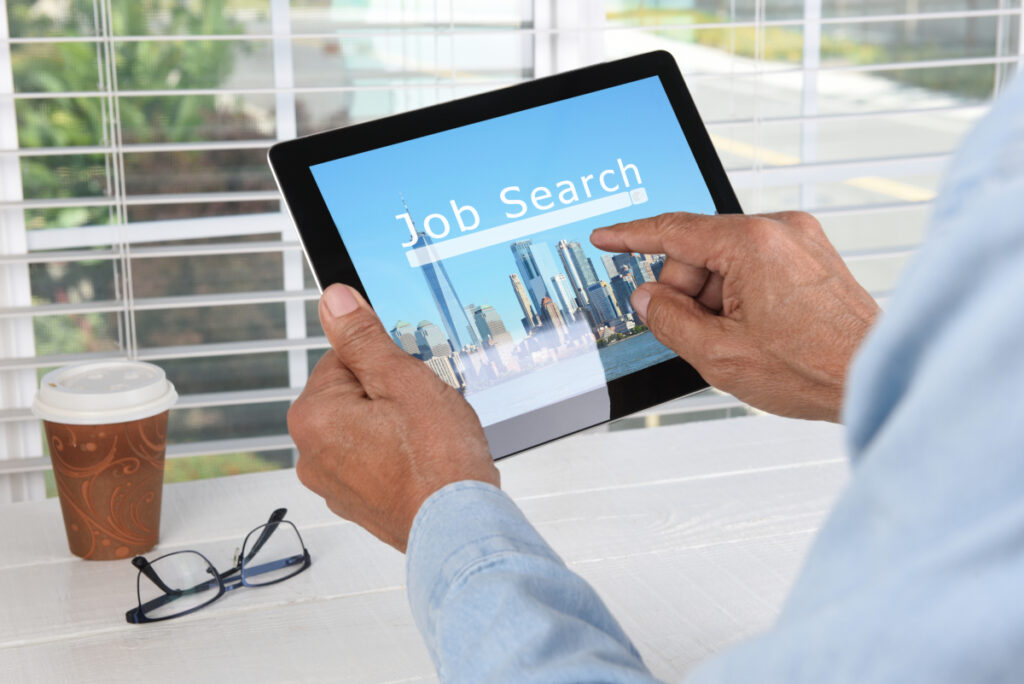 Person searching online for career opportunities on a tablet, showing how to find a job in Oklahoma using digital tools.