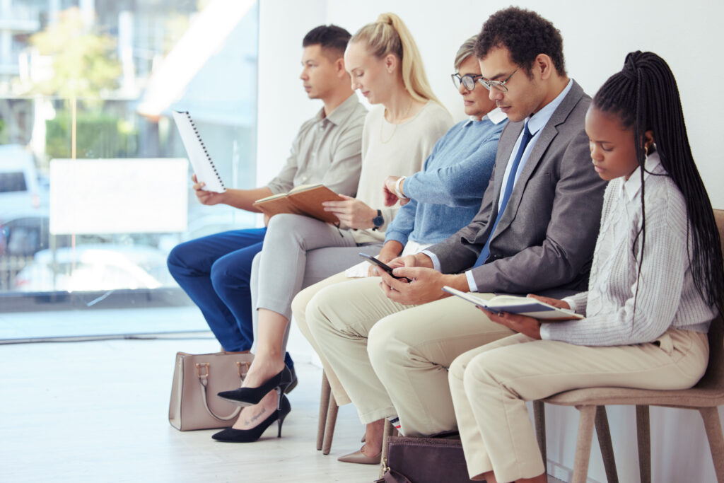 Job candidates waiting for interviews with an employment agency while preparing resumes and job interview prep materials with staffing experts